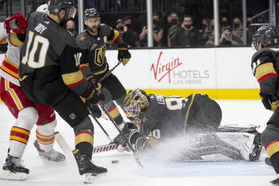 Vegas Golden Knights goaltender Robin Lehner (90) saves a shot on goal by Calgary Flames center Mikael Backlund, left, during the third period of an NHL hockey game Sunday, Dec. 5, 2021, in Las Vegas. Vegas Golden Knights center Nicolas Roy (10) and Vegas Golden Knights defenseman Alex Pietrangelo, behind, defend the goal. (AP Photo/Ellen Schmidt)