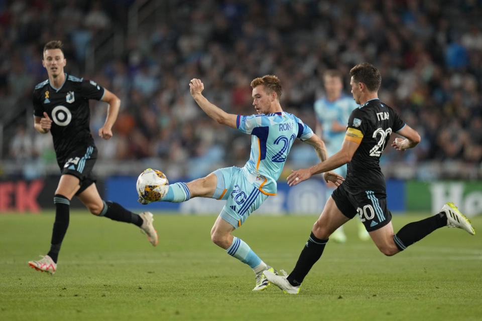 Colorado Rapids midfielder Connor Ronan (20), center, passes while challenged by Minnesota United midfielder Will Trapp (20), right, during the first half of an MLS soccer match, Wednesday, Aug. 30, 2023, in St. Paul, Minn. (AP Photo/Abbie Parr)