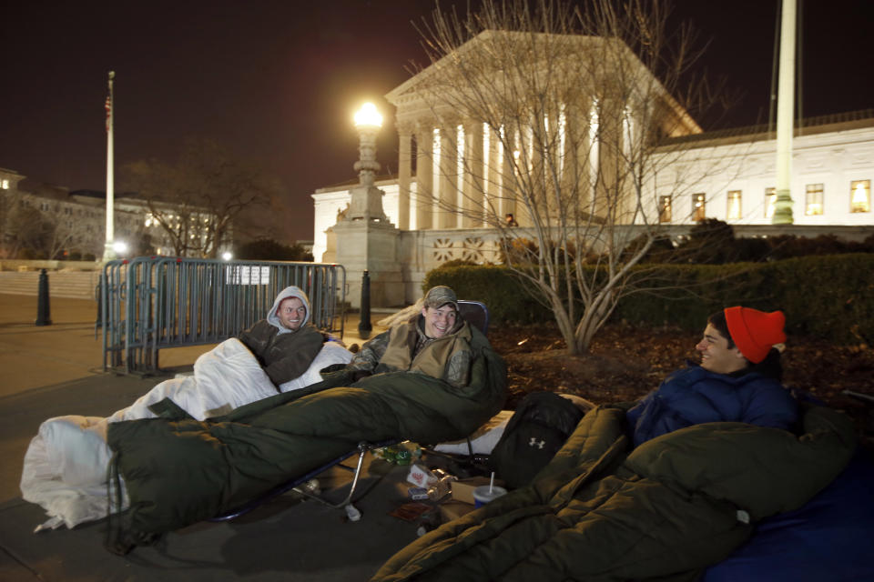 Brandon, left, from Warrenton, Va., sits with Matt and Zack, both from Nokesville, Va., as they wait in line in front of the Supreme Court, Monday, March 24, 2014, in Washington. The men arrived Friday afternoon to be first in line. The Supreme Court is weighing whether corporations have religious rights that exempt them from part of the new health care law that requires coverage of birth control for employees at no extra charge. (AP Photo/Alex Brandon)