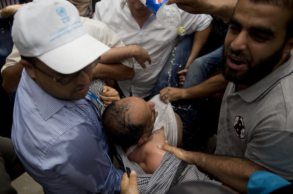 Palestinians prevent an UNWRA employee form setting himself on fire employee sits during a protest at the United Nations agency for Palestinian refugees (UNRWA) headquarters in Gaza City, Wednesday, July 25, 2018. UNWRA staff are protesting the agency's decision to fire dozens of Palestinian staff in Gaza in the Gaza Strip. (AP Photo/Khalil Hamra)