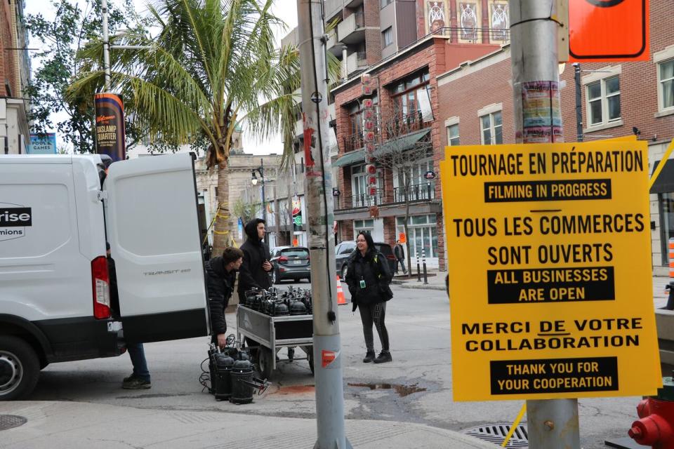 Signs let passersby know that stores are still open during filming on Ste-Catherine Street E.