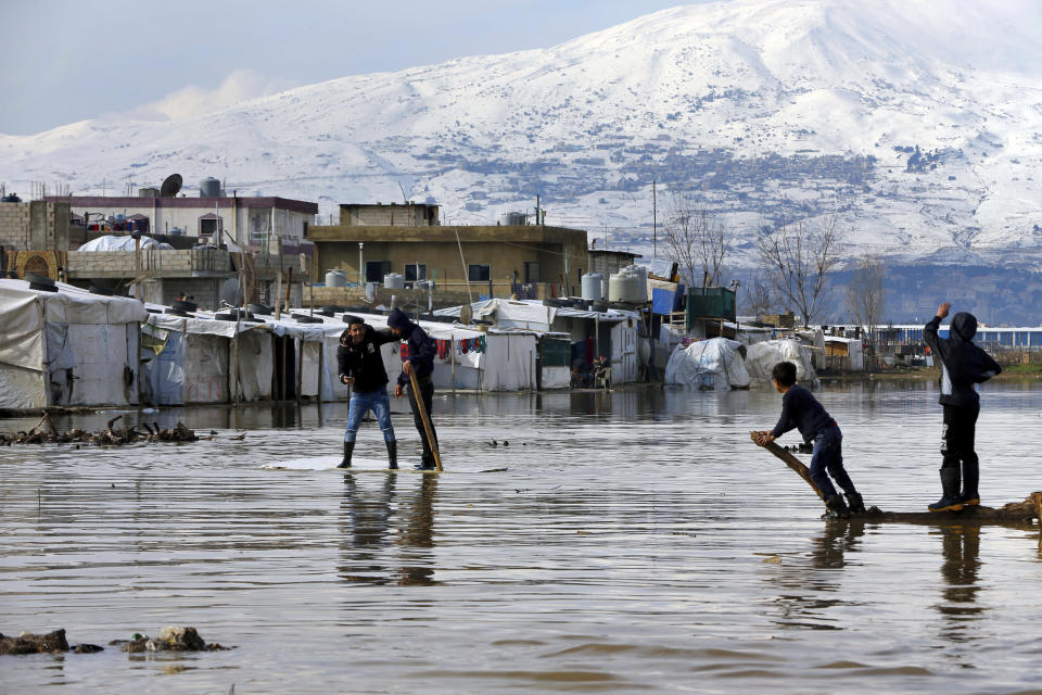 Syrian refugees use a floating piece of wood to move around after heavy rain caused floods at a refugee camp, in the town of Bar Elias, in the Bekaa Valley, Lebanon, Thursday, Jan. 10, 2019. A storm that battered Lebanon for five days displaced many Syrian refugees after their tents got flooded with water or destroyed by snow. (AP Photo/Bilal Hussein)