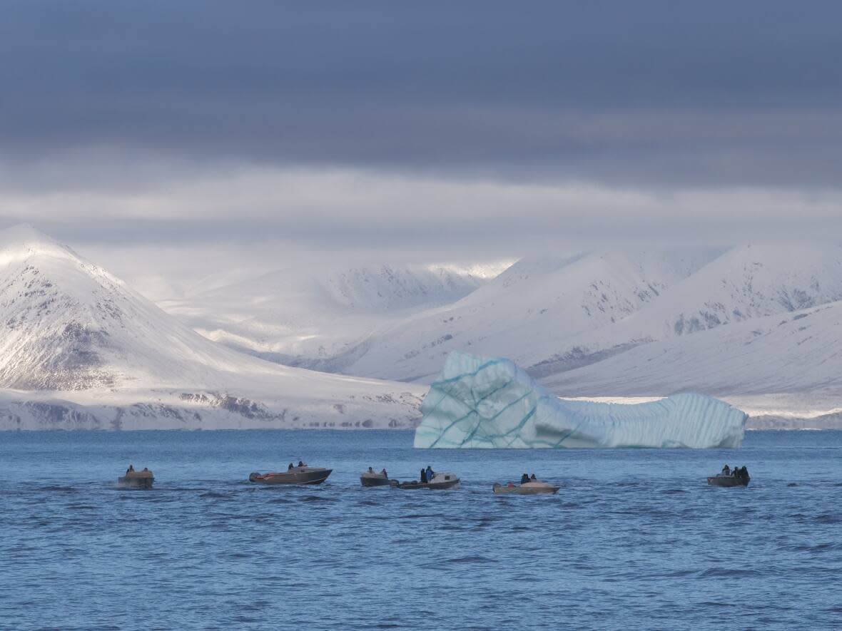 Boaters in Eclipse Sound outside of Pond Inlet, Nunavut, with Bylot Island in the background. A new study says an international policy meant to protect and heal a hole in the ozone layer is also delaying the Arctic's first ice-free summer.  (David Gunn/CBC - image credit)