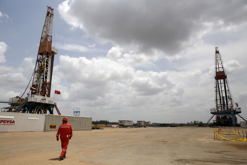 FILE PHOTO: An oilfield worker walks next to drilling rigs at an oil well operated by Venezuela's state oil company PDVSA, in the oil rich Orinoco belt, near Morichal at the state of Monagas