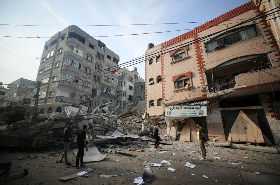 巴勒斯坦人站在伊斯蘭國家銀行大樓廢墟旁