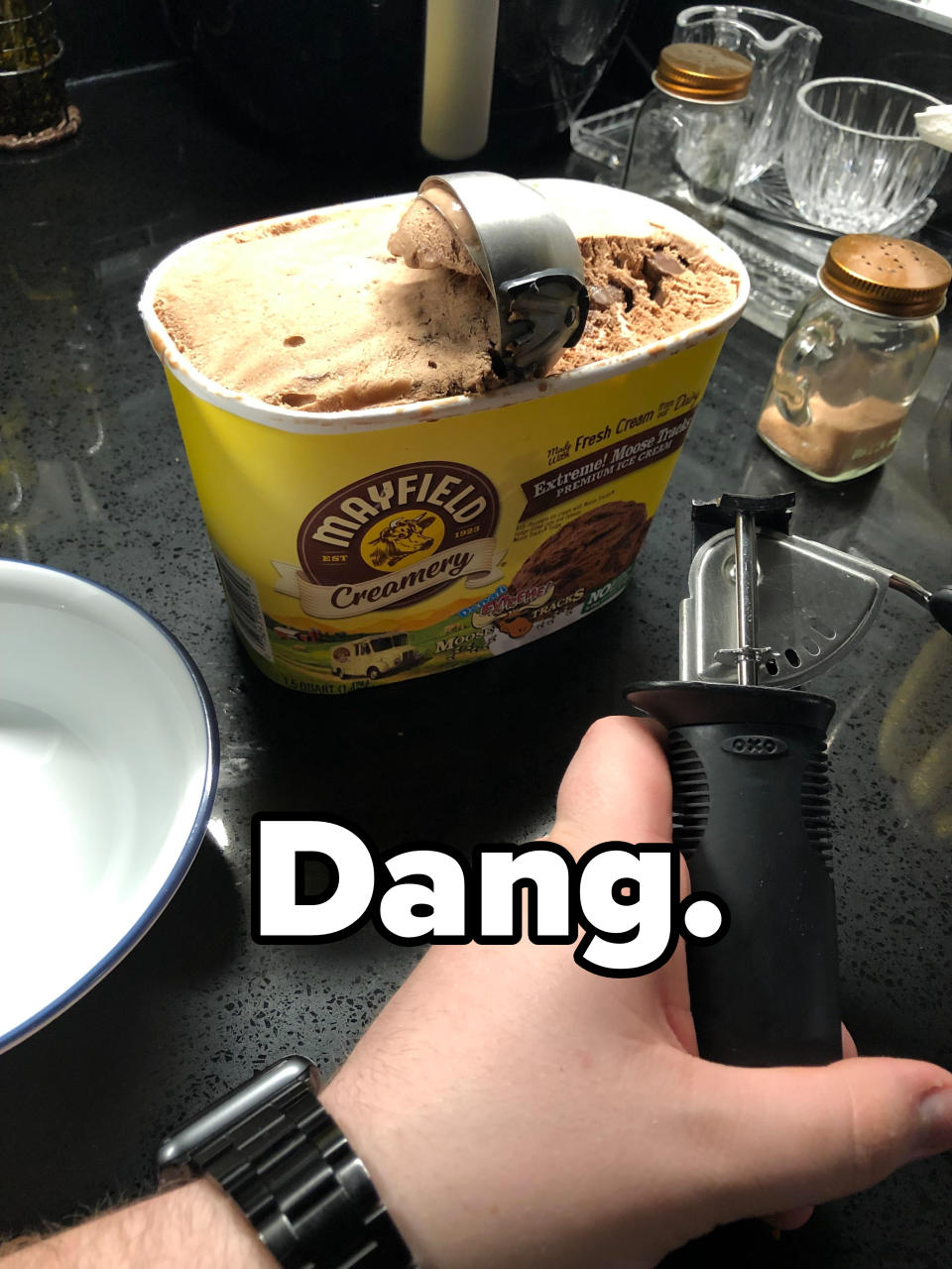 Person scooping from a large tub of Mayfield Creamery ice cream with a kitchen scoop