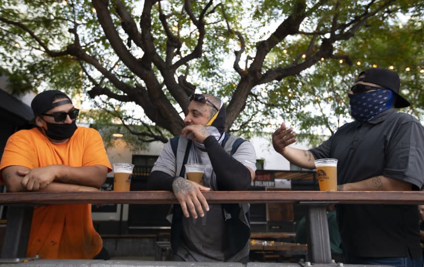 LOS ANGELES, CA - JUNE 30: Adan Gutierrez, left, Ramon Ayala, middle, and Vicente Fernandez, right, enjoy a beer outside the Central Market during the evening on Tuesday, June 30, 2020 in Los Angeles, CA. They were all wearing masks and keeping a distance for one another. Inside the brewery remains open because they also sell food. Citing the rapid pace of coronavirus spread in some parts of California, Gov. Gavin Newsom ordered seven counties including Los Angeles on Sunday to immediately close any bars and nightspots that are open and recommended eight other counties take action on their own to close those businesses. (Francine Orr / Los Angeles Times)