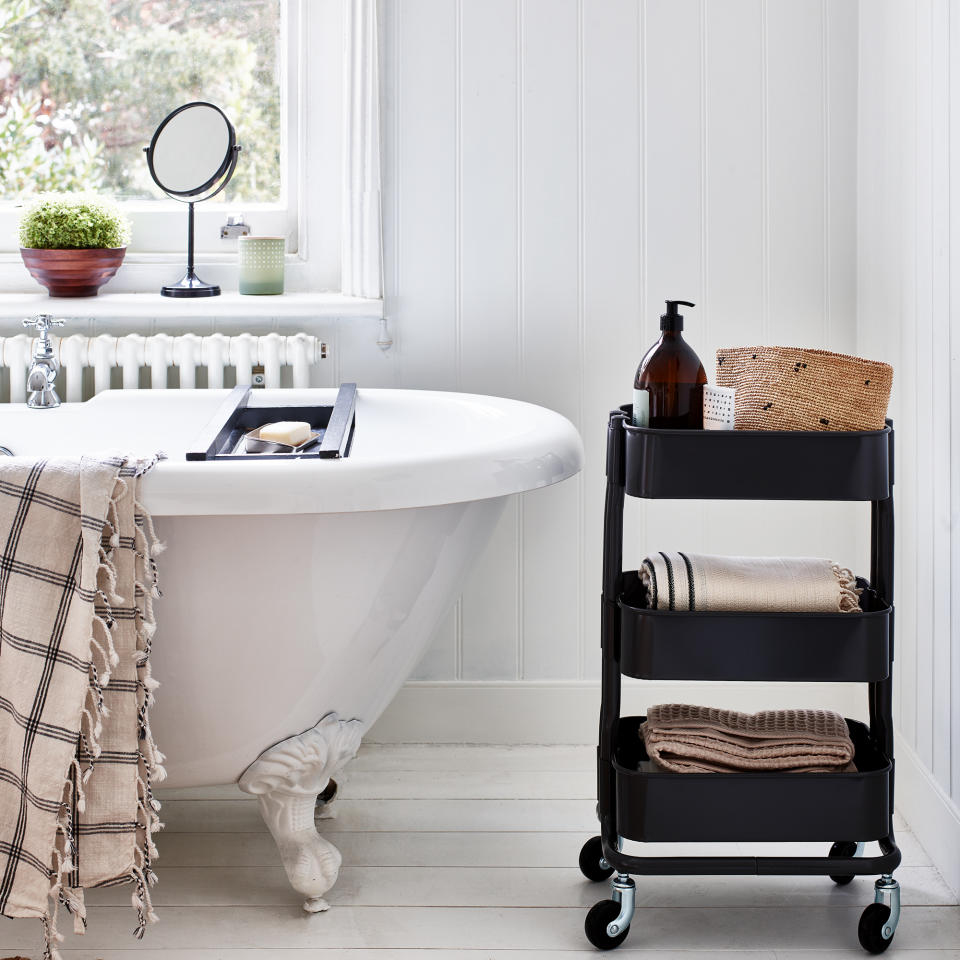 White bathroom with bathtub and black rolling storage