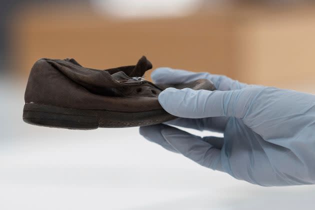 A worker holds a shoe that belonged to a child victim of the former Nazi German death camp Auschwitz-Birkenau at the conservation laboratory on the grounds of the camp.
