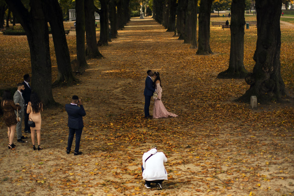 A couple wearing wedding outfits pose for photos at Cinquantenaire park in an autumn day in Brussels, Friday, Oct. 23, 2020. Belgian Prime Minister Alexander De Croo stopped short Friday of imposing another full lockdown, as the country did in March, but introduced a series of new restrictive measures as the number of COVID-19 related hospital admissions and deaths continue to soar. (AP Photo/Francisco Seco)