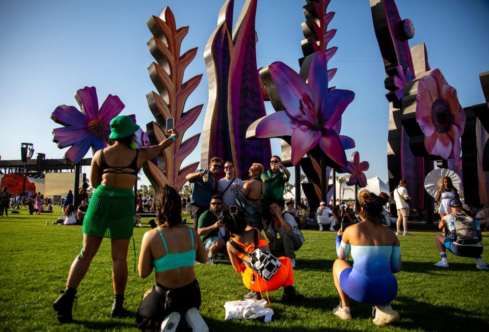 A group of traveling festival friends pose together for photos in front of 'Eden' by Maggie West during the Coachella Valley Music and Arts Festival at the Empire Polo Club in Indio, Calif., Friday, April 14, 2023.