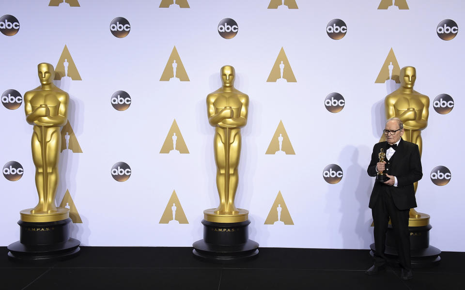 FILE - In this Sunday, Feb. 28, 2016 file photo, Ennio Morricone poses in the press room with the award for best original score for "The Hateful Eight" at the Oscars at the Dolby Theatre in Los Angeles. Morricone, who created the coyote-howl theme for the iconic Spaghetti Western “The Good, the Bad and the Ugly” and the soundtracks such classic Hollywood gangster movies as “The Untouchables,” died Monday, July 6, 2020 in a Rome hospital at the age of 91. (Photo by Jordan Strauss/Invision/AP)