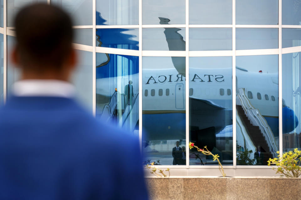 A member of Diplomatic Security stands guard on the tarmac as the plane for Secretary of State Mike Pompeo is reflected in a glass building, in preparation for Pompeo's departure from Abu Dhabi, United Arab Emirates, Tuesday, June 25, 2019, from where he will head to an undisclosed location. (AP Photo/Jacquelyn Martin, Pool)