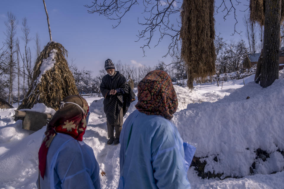 An elderly Kashmiri man who refused to get vaccinated talks to healthcare workers during a COVID-19 vaccination drive in Budgam, southwest of Srinagar, Indian controlled Kashmir, Jan. 11, 2022. (AP Photo/Dar Yasin)