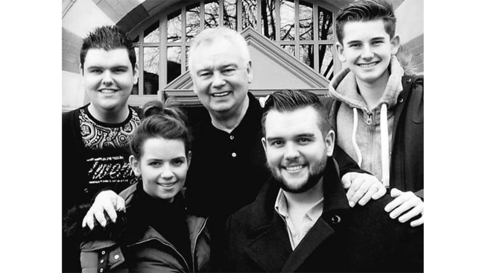 Black and white photo showing Eamonn Holmes posing with his four children