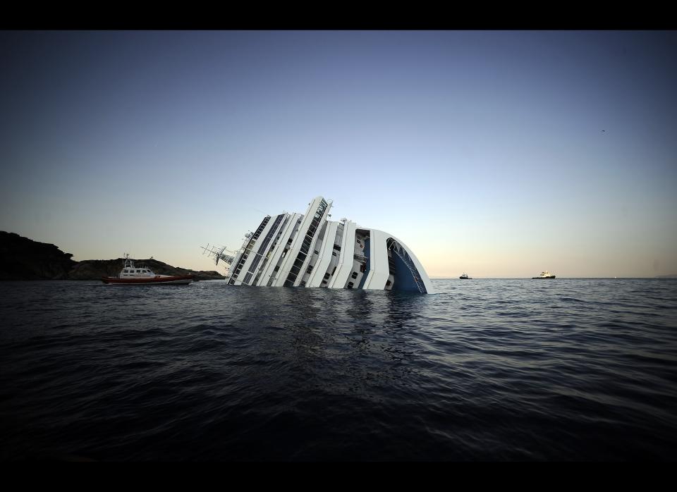 View of the Costa Concordia on January 14, 2012, after the cruise ship ran aground and keeled over off the Isola del Giglio, last night. Three people died and several were missing after the ship with more than 4,000 people on board ran aground sparking chaos as passengers scrambled to get off. AFP PHOTO / FILIPPO MONTEFORTE
