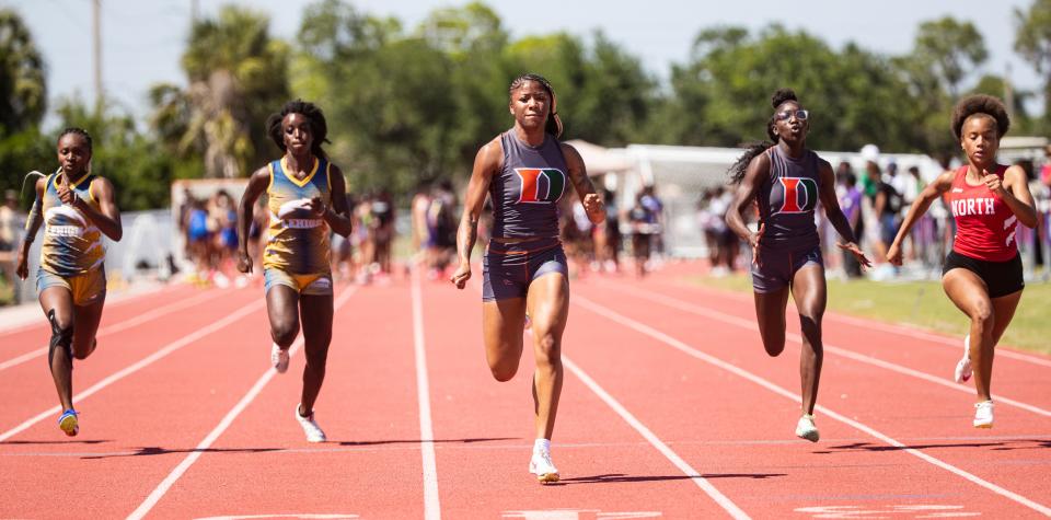 Kayla Hopkins, center, of Dunbar High School wins the girls 100 during the LCAC Track and Field Championships at Cypress Lake High School on Wednesday, April 17, 2024.