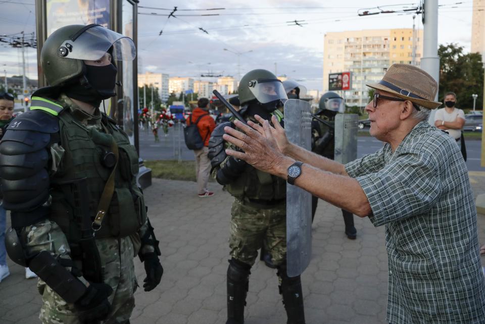 A elderly man gestures as he taks with riot police officers in the capital of Minsk, Belarus, Tuesday, Aug. 11, 2020. Heavy police cordons blocking Minsk's central squares and avenues didn't discourage demonstrators who again took to the streets chanting "Shame!" and "Long live Belarus!" as police moved quickly Tuesday to separate and disperse scattered groups of protesters in the capital, but new pockets of resistance kept mushrooming across downtown Minsk.(AP Photo/Sergei Grits)