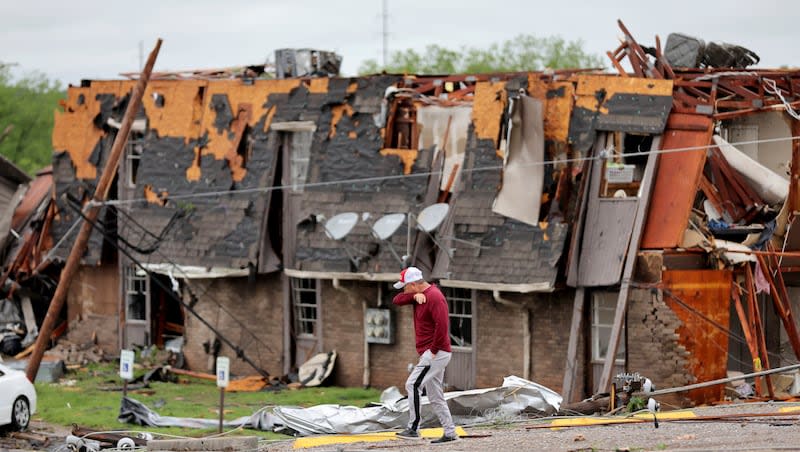 A man walks past tornado damage in Sulphur, Okla., Sunday, April 28, 2024, after severe storms hit the area the night before.