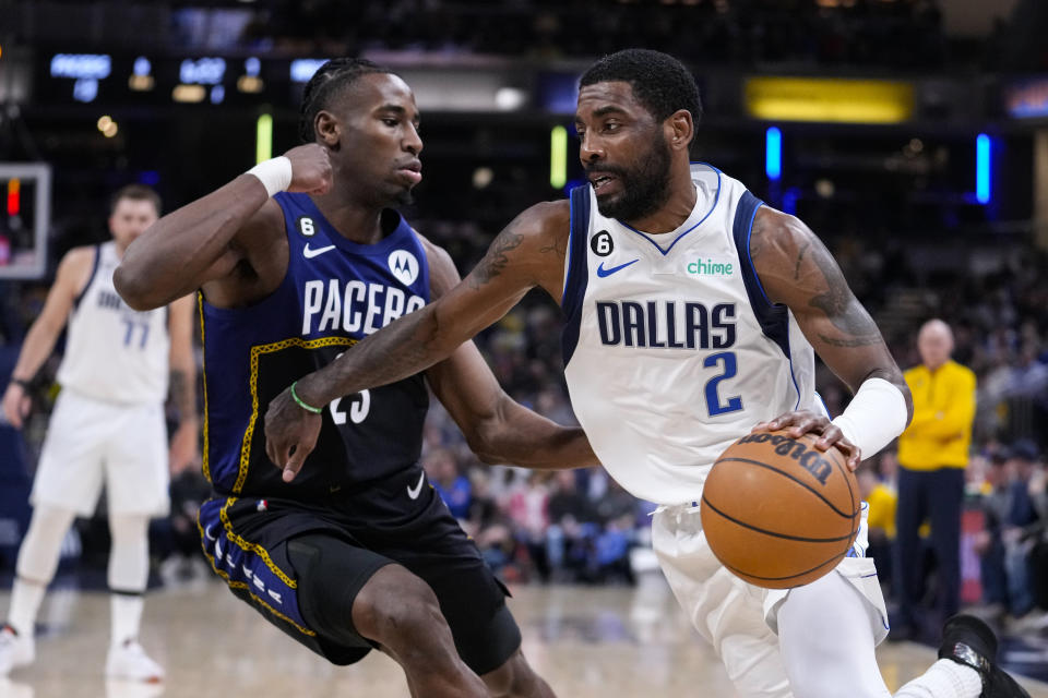 Dallas Mavericks guard Kyrie Irving (2) drives on Indiana Pacers forward Aaron Nesmith (23) during the first half of an NBA basketball game in Indianapolis, Monday, March 27, 2023. (AP Photo/Michael Conroy)