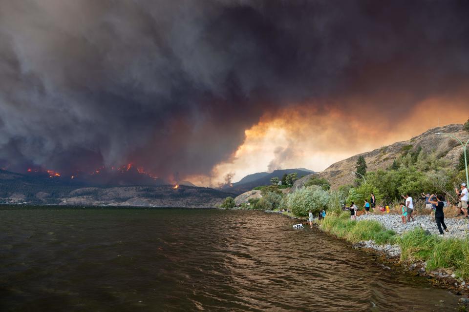 Residents watch the McDougall Creek wildfire in West Kelowna, British Columbia, Canada, on August 17, 2023, from Kelowna. Evacuation orders were put in place for areas near Kelowna, as the fire threatened the city of around 150,000. Canada is experiencing a record-setting wildfire season, with official estimates of over 13.7 million hectares (33.9 million acres) already scorched. Four people have died so far. (Photo by Darren HULL / AFP) (Photo by DARREN HULL/AFP via Getty Images)