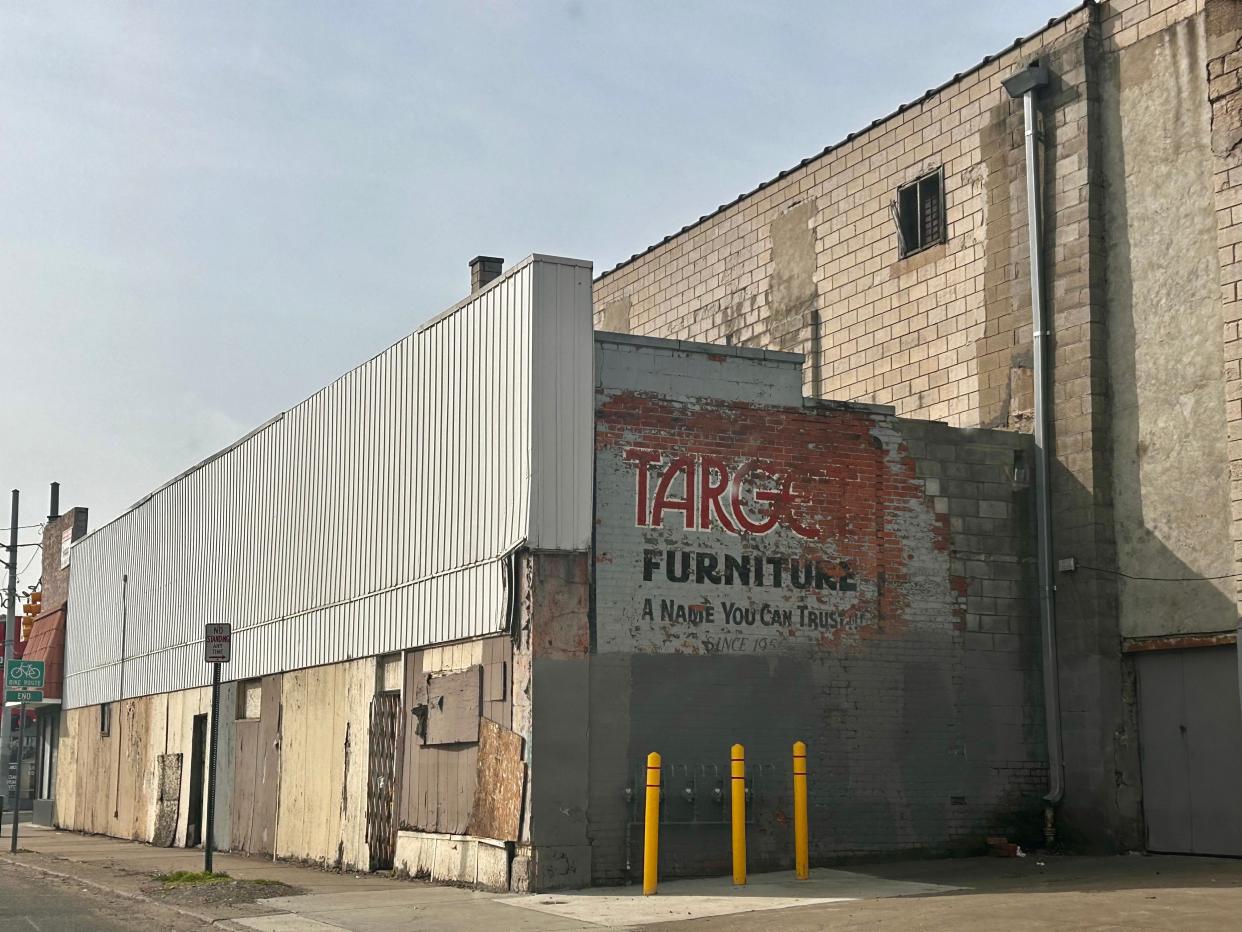 A ghost sign reading "Target Furniture: A Name You Can Trust Since 1956" faces the back of an empty building at the corner of Central Avenue and Vernor Highway in southwest Detroit.
