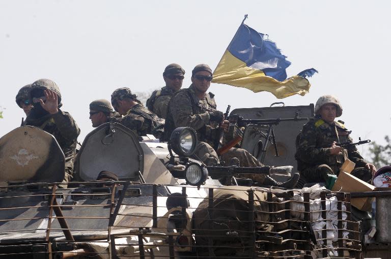 Ukrainian soldiers sit on the top of a armoured personnel carrier as they patrol in Donetsk region on September 3, 2014