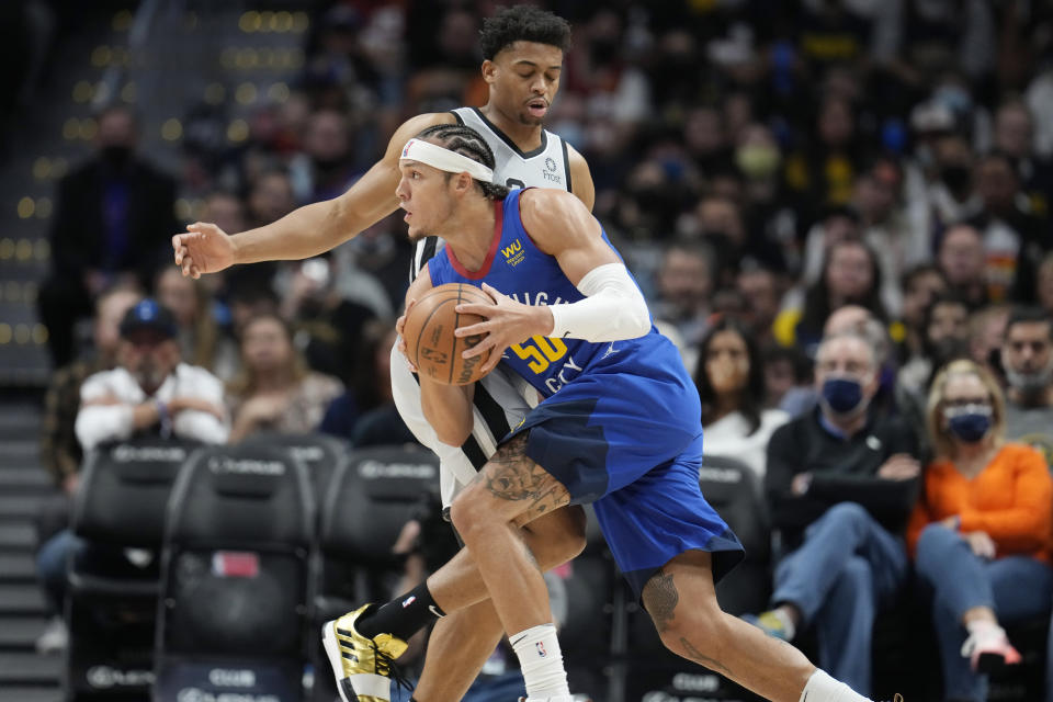 Denver Nuggets forward Aaron Gordon, front, drives past San Antonio Spurs forward Keldon Johnson during the first half of an NBA basketball game Friday, Oct. 22, 2021, in Denver. (AP Photo/David Zalubowski)