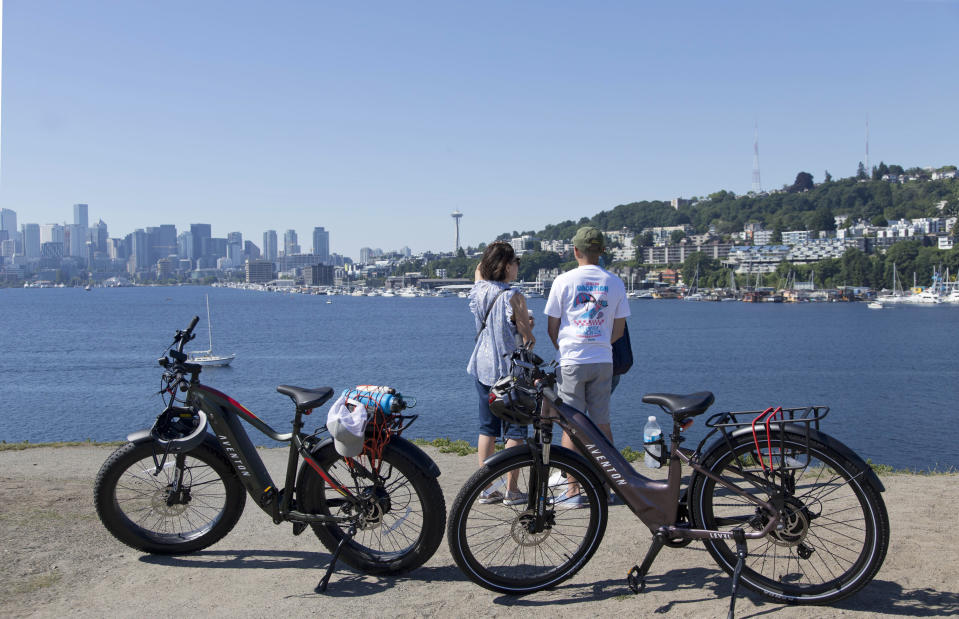 Vivian Unsay, left, Gene Unsay, right, back, of Guam look over Lake Union along with their son Francis Unsay of Seattle in the morning during a heat wave hitting the Pacific Northwest, Sunday, June 27, 2021, in Seattle. Yesterday set a record high for the day with more record highs expected today and Monday. (AP Photo/John Froschauer)