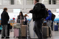Travelers check their tickets at the O'Hare International Airport in Chicago, Thursday, Dec. 21, 2023. It's beginning to look a lot like a hectic holiday travel season, but it might go relatively smoothly if the weather cooperates. (AP Photo/Nam Y. Huh)