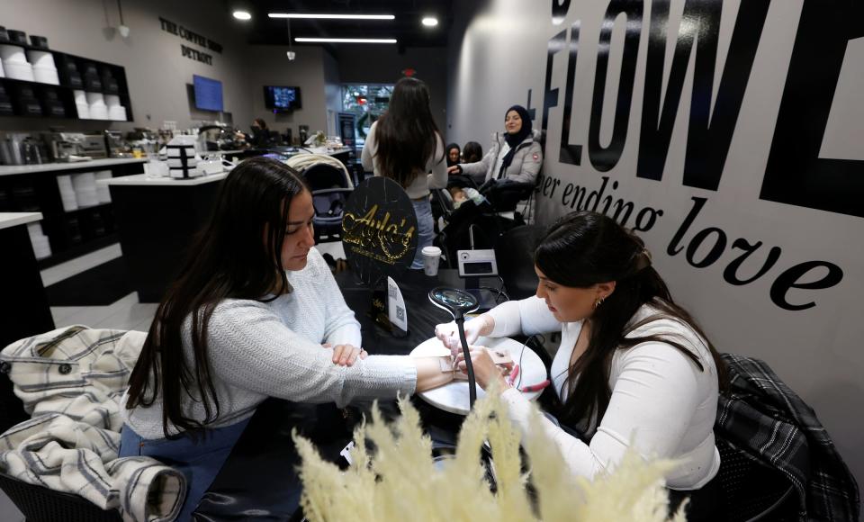 Diebh Faraj, 30, of Dearborn, left, gets permanent jewelry put on by Zainab Sobh, 25, of Canton, owner of Ayla's Links, during her pop-up location inside of The Flower Shop Detroit in Dearborn Heights on Dec. 9, 2022. The store that is a florist and a coffee shop in one opened up in October 2022.