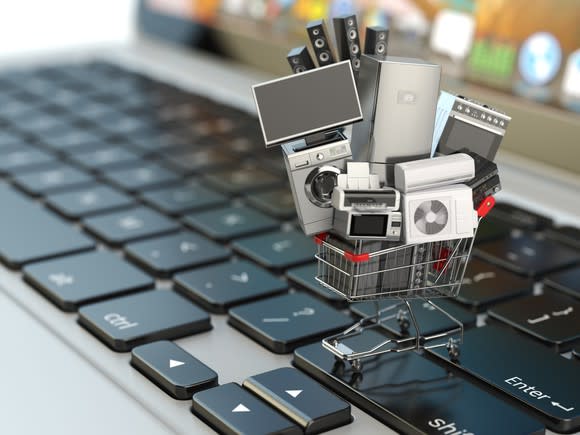Miniature shopping cart full of electronics on a keyboard