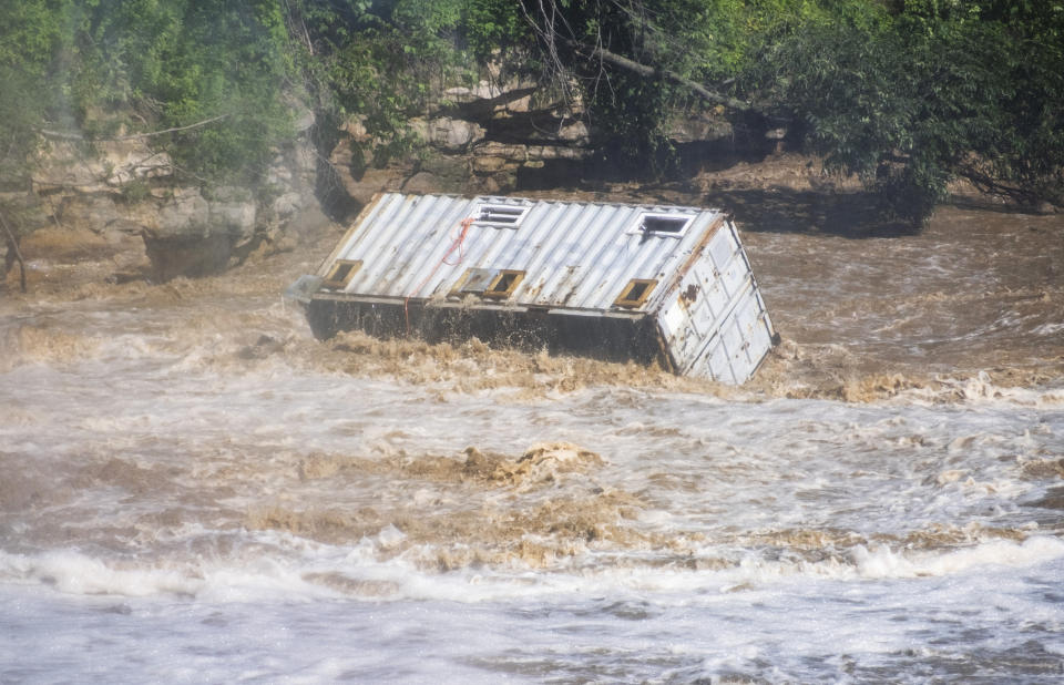 A shipping container barrels down the Blue Earth River, Monday, June 24, 2024, in Rapidan, Minn., after waters from the waterway diverted the Rapidan Dam, causing massive damage to the western cliffs. (Casey Ek/The Free Press via AP)
