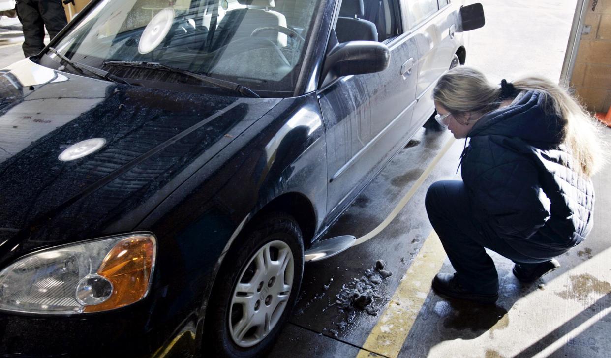 An E-Check inspector examines a car at the Pinnacle Parkway E-Check station in Twinsburg. [Mike Cardew/Beacon Journal file photo]