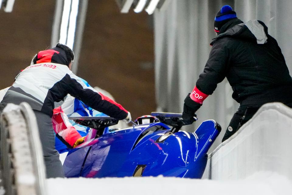 Track assistants tend to the bobsled of Brad Hall and Nick Gleeson (AP)