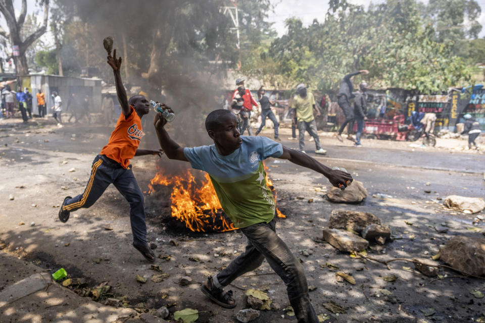 Protesters throw rocks towards police in the Kibera slum of Nairobi, Kenya Monday, March 20, 2023. Hundreds of opposition supporters have taken to the streets of the Kenyan capital over the result of the last election and the rising cost of living, in protests organized by the opposition demanding that the president resigns from office. (AP Photo/Ben Curtis)