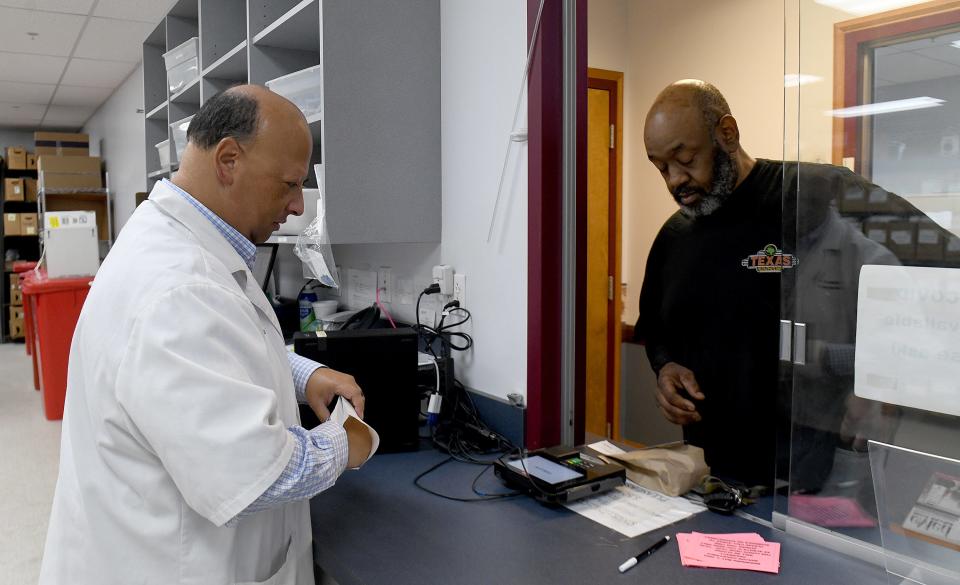 Phamacist William Hubert works with client David Wiggins of Canton at Beacon Charitable Pharmacy in Canton. Cleveland Clinic Mercy Hospital recently donated a former physician's office building on 13th Street NW to serve as a new home for the pharmacy.