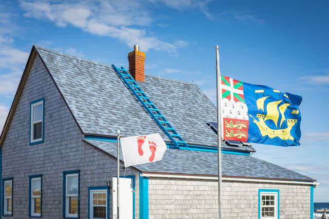 <p>Mathieu Dupuis/Legendary Coasts CVB</p> Flags flying in front of a house on Miquelon.