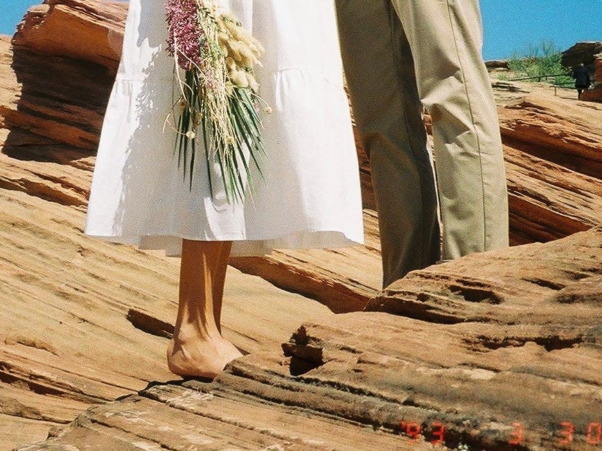 A woman in a white dress and flowers standing next to a man.