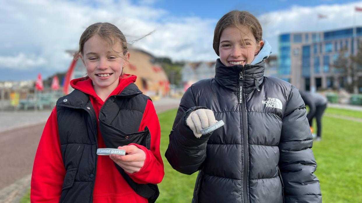 Zara is on the left handside of the photos and Florence is on the right, they're holding up with silver wristbands and smiling wrapped up warm as Zara's fringe blows in the wind