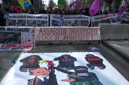 Kurdish people display a poster showing comics of Turkish President Tayyip Erdogan during a protest outside an EU leaders summit addressing the influx of refugees and migrants flowing into Europe, in Brussels March 17, 2016. REUTERS/Yves Herman