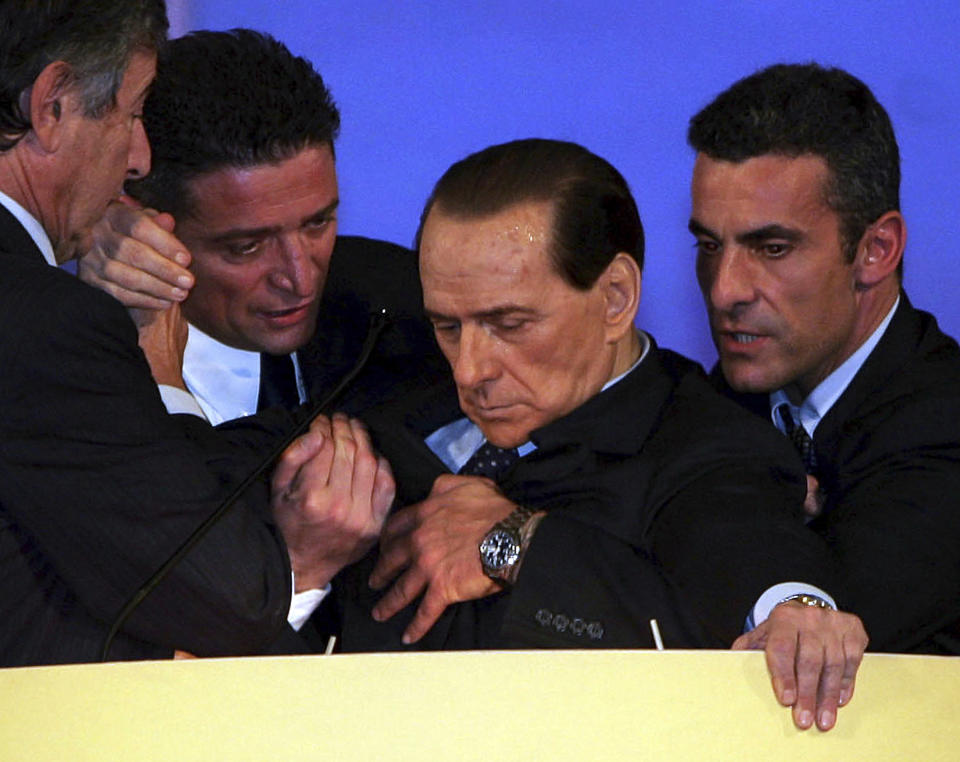 FILE - Former Italian Premier Silvio Berlusconi, second from right, is supported at the podium by his personal doctor Umberto Scapagnini, left, and by two unidentified men, as he slumped during an emotional speech to political supporters in Montecatini Terme, Italy, on Nov. 26, 2006. Berlusconi, the boastful billionaire media mogul who was Italy's longest-serving premier despite scandals over his sex-fueled parties and allegations of corruption, died, according to Italian media. He was 86. (AP photo/Fabrizio Giovannozzi, File)