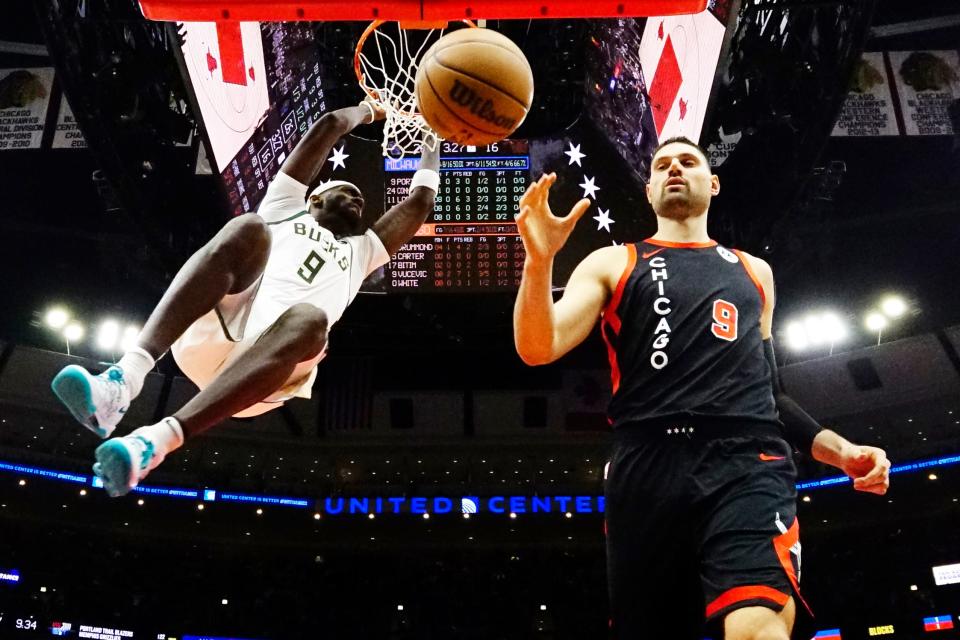 Bucks forward Bobby Portis hangs on the rim after throwing down a dunk as Bulls center Nikola Vucevic collects the ball during the first quarter Saturday night at United Center.