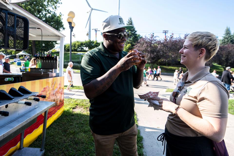 Ian Robertson takes a bite of the OMG chicken sandwich while his wife, Jess Robertson, watches on Day 1 of the Iowa State Fair.