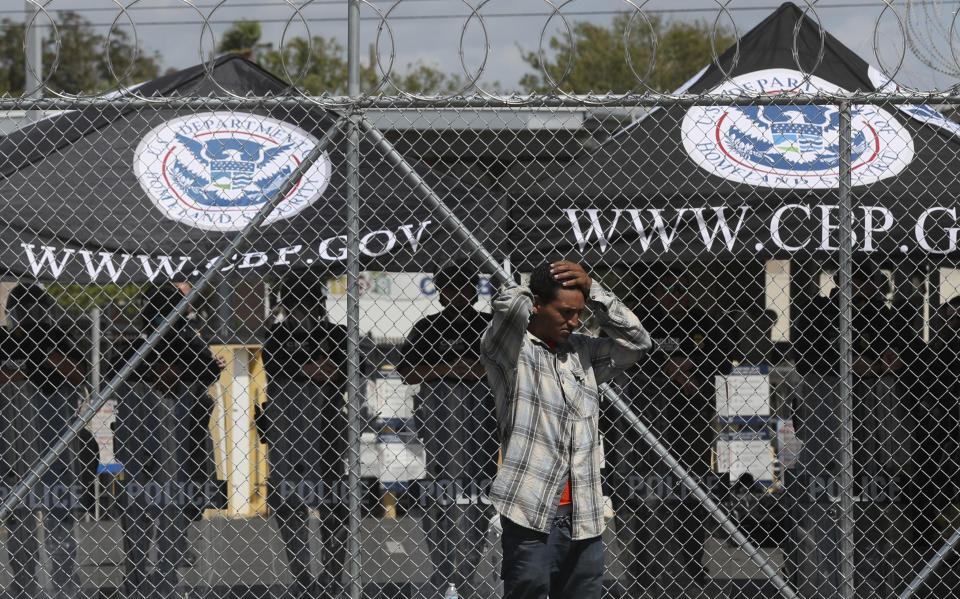 A migrant grabs his head as he stands next to the fence closing the Gateway International Bridge that connects downtown Matamoros, Mexico with Brownsville, Thursday, Oct. 10, 2019. Migrants wanting to request asylum camped out on the international bridge leading from Mexico into Brownsville, Texas, causing a closure of the span. (AP Photo/Fernando Llano)