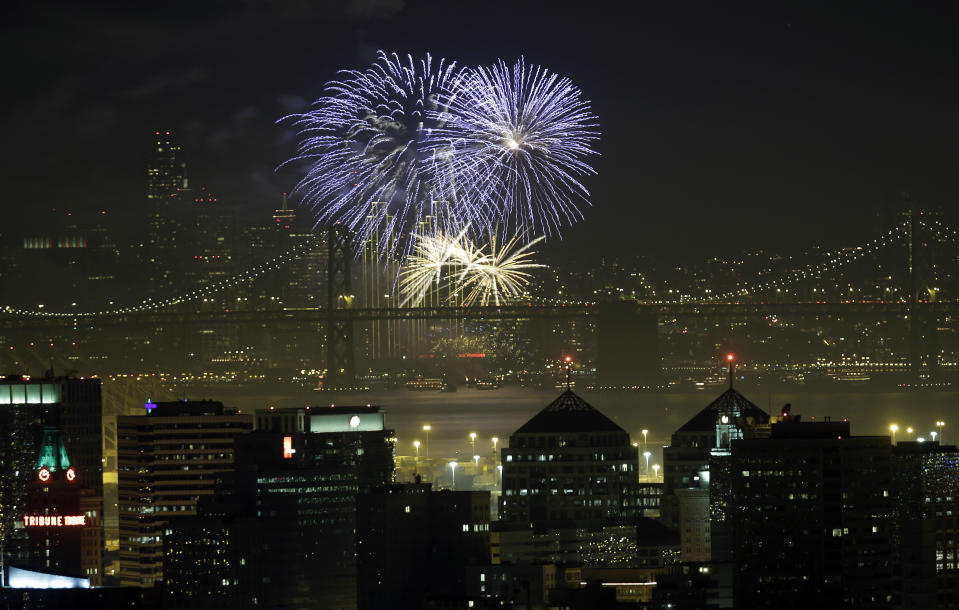 Fireworks fill the air in the bay over the Oakland, bottom, and San Francisco skylines, divided by the San Francisco Oakland Bay Bridge, as part of New Year's Eve celebrations in a view from Oakland, Calif. on Wednesday, Jan. 1, 2014. (AP Photo/Marcio Jose Sanchez)