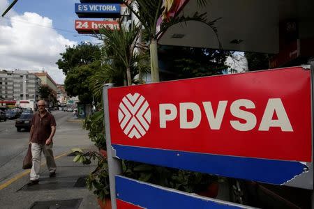 FILE PHOTO: A man walks past the corporate logo of the state oil company PDVSA at a gas station in Caracas, Venezuela December 1, 2017. REUTERS/Marco Bello/File Photo