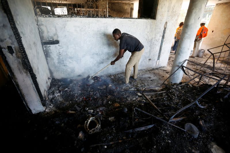 A man removes burning debris inside a bedroom at an orphanage after it was destroyed in a fire, in Port-au-Prince