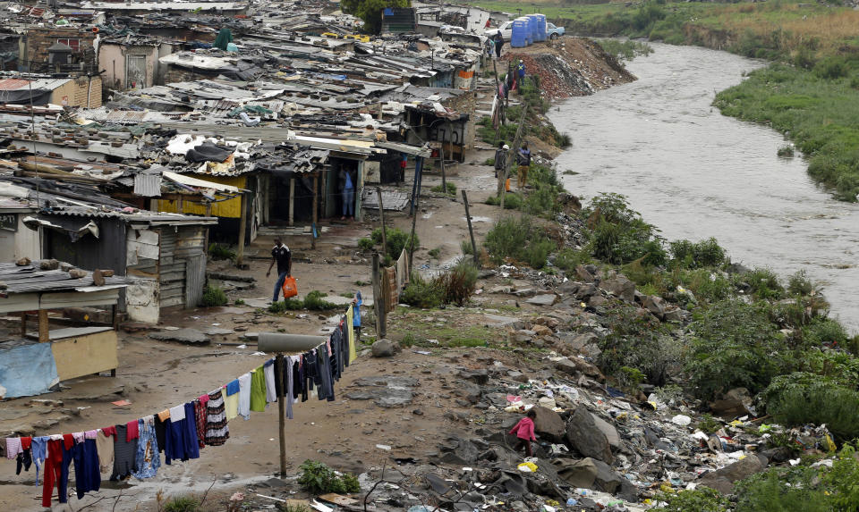 FILE — A man walks along an informal settlement as a young girl plays next to the polluted Jukskei River in Alexandra, northern Johannesburg, South Africa Nov. 11, 2014. On Saturday, April 27, 2024 the country will celebrate Freedom Day when In 1994 people braved long queues to cast votes after years of white minority rule which denied Black South Africans the right to vote. (AP Photo/Themba Hadebe/File)