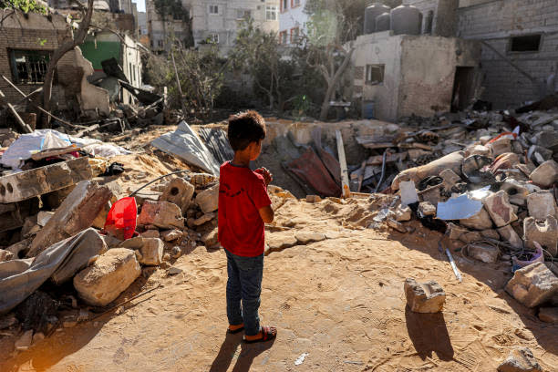 A boy stands before an impact crater at the site of a building that was hit by Israeli bombardment in Rafah in the southern Gaza Strip on 8 May 2024 (AFP via Getty Images)
